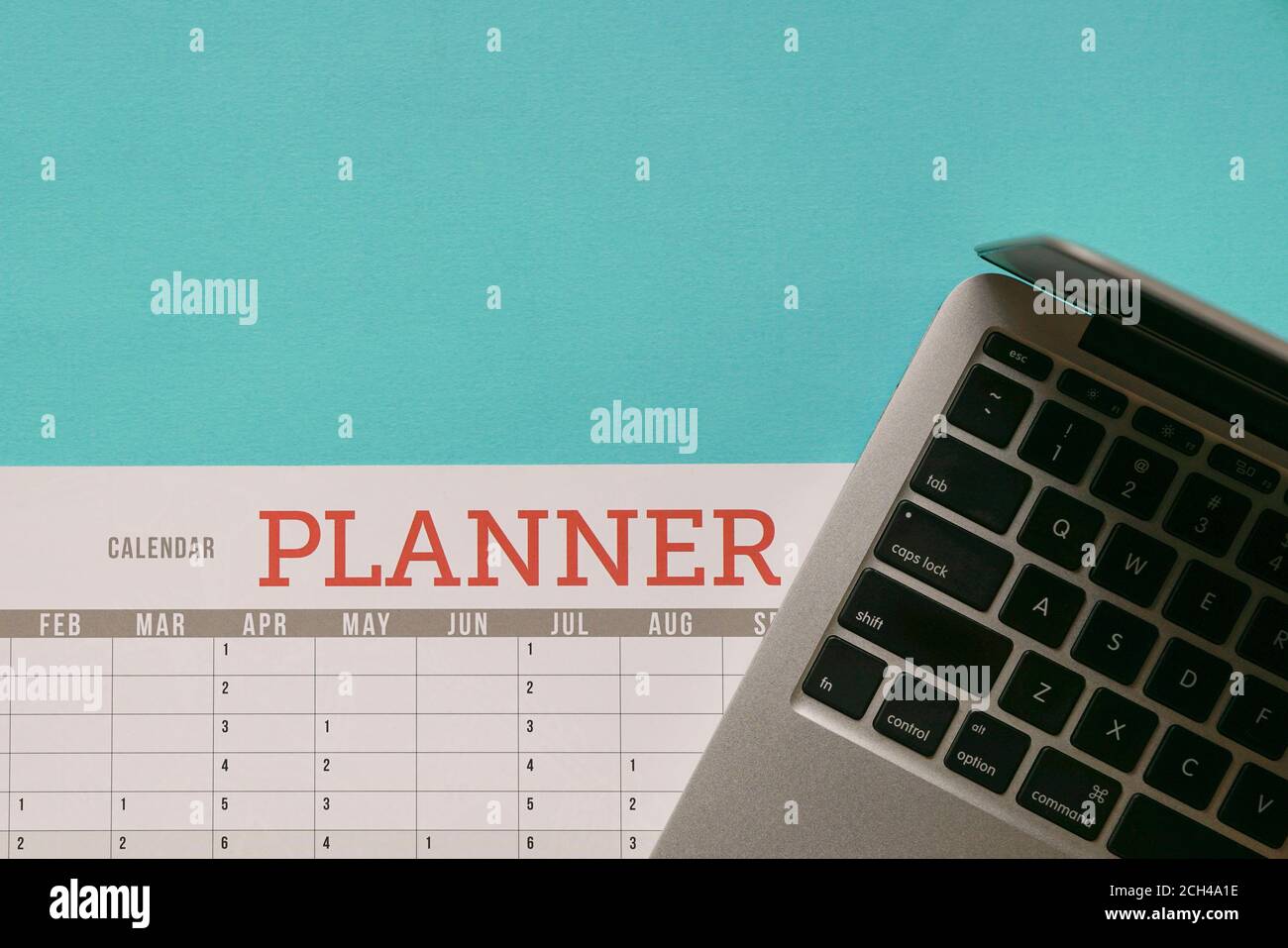 Computer laptop on top of calendar planner and blue tabletop. Business