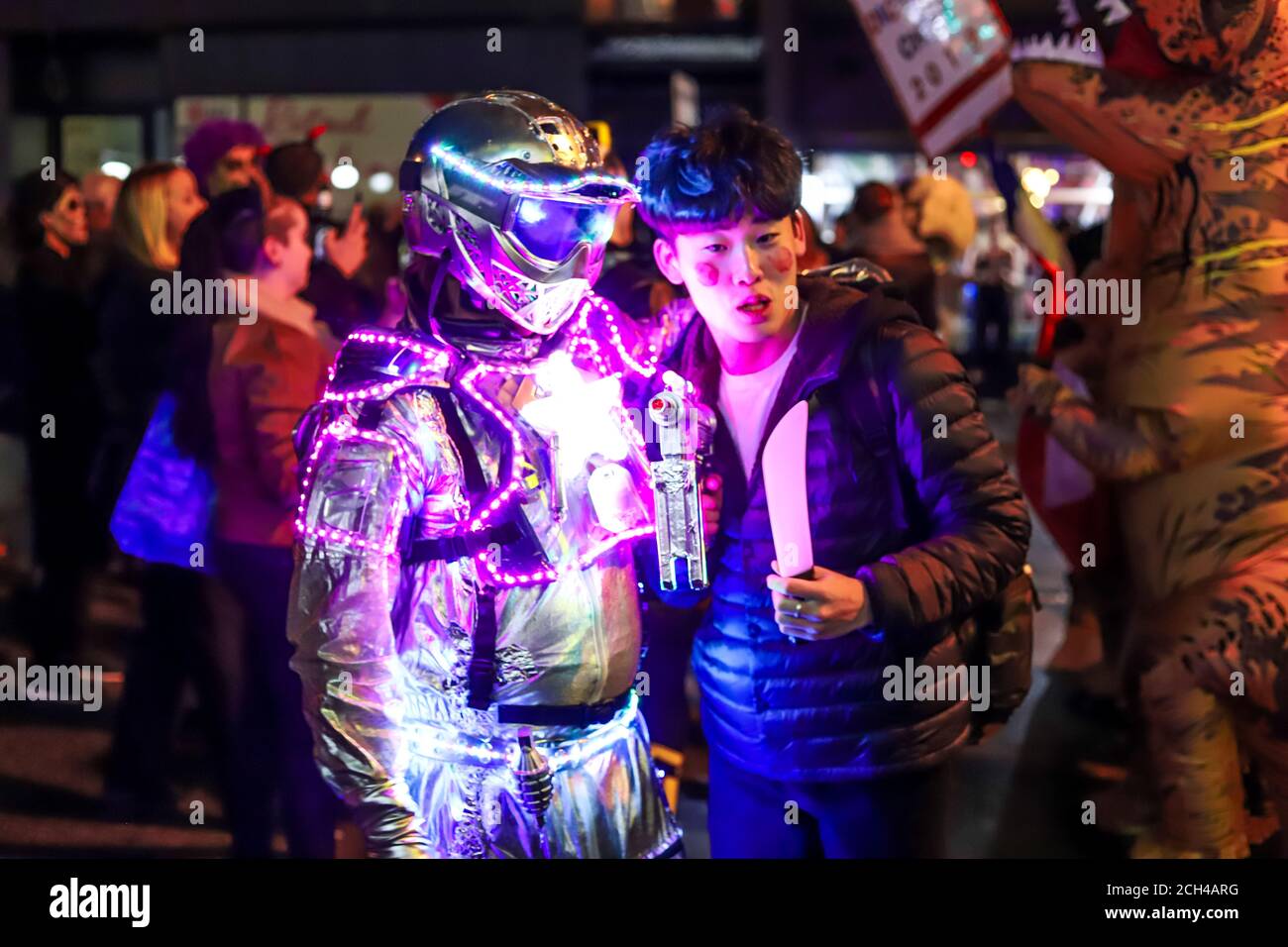 Halloween night carnival . Church street, people walking in different masks and costumes. Stock Photo