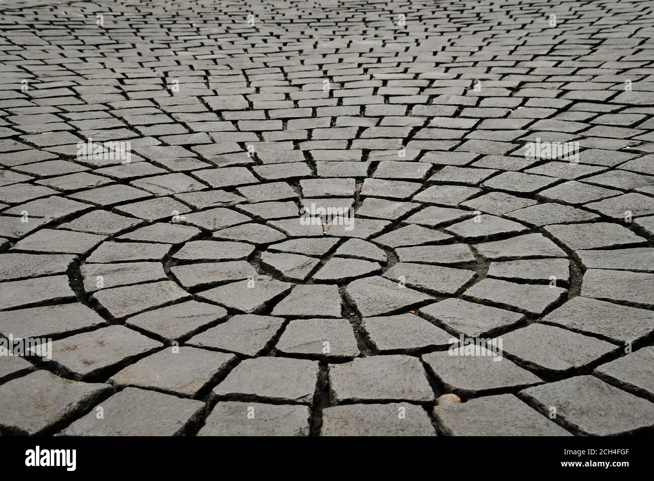 A ground level perspective view of grey stone paving cobbles in a
