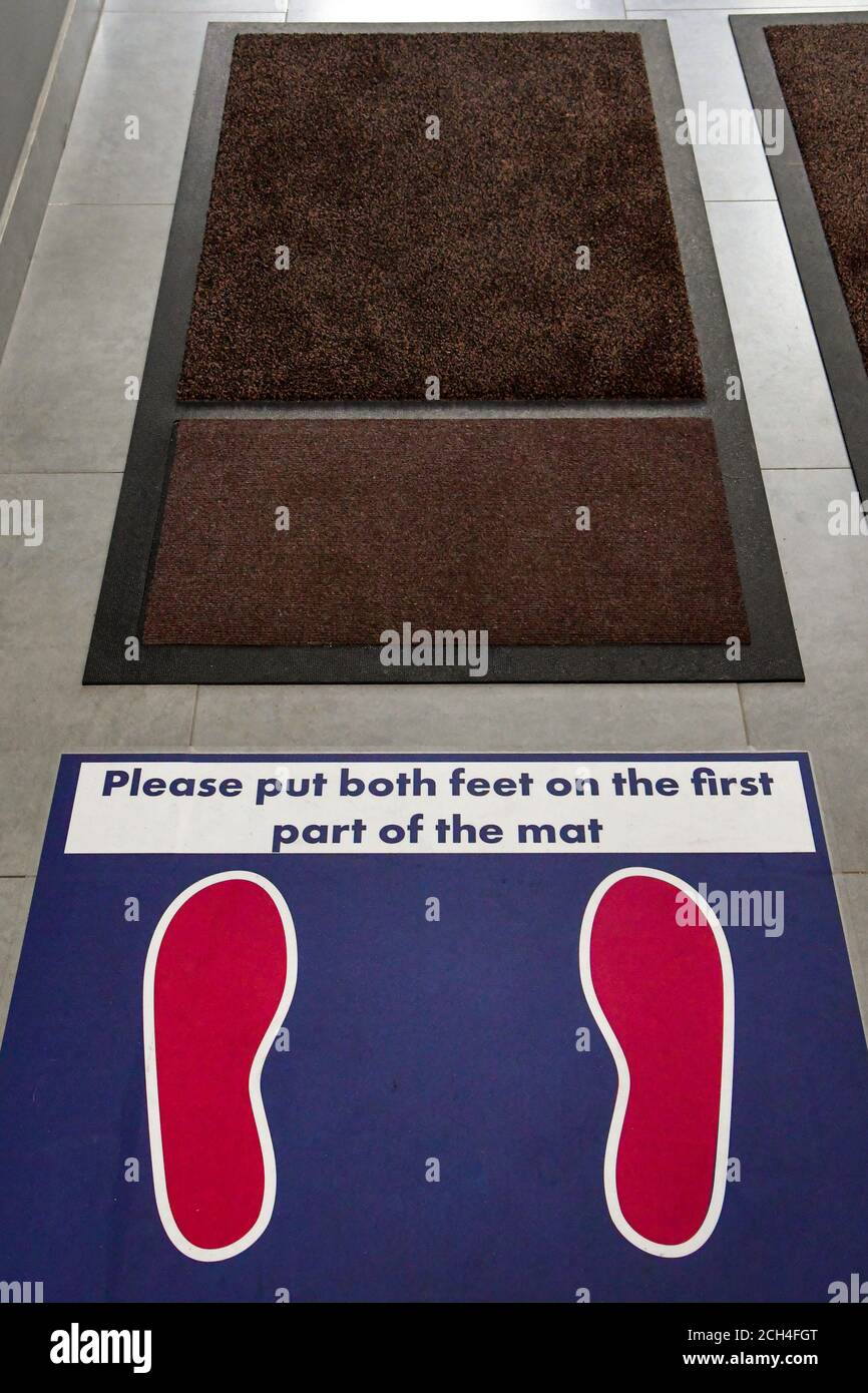 Floor markings and instructions for shoe sanitizing mats in an office building during the covid
