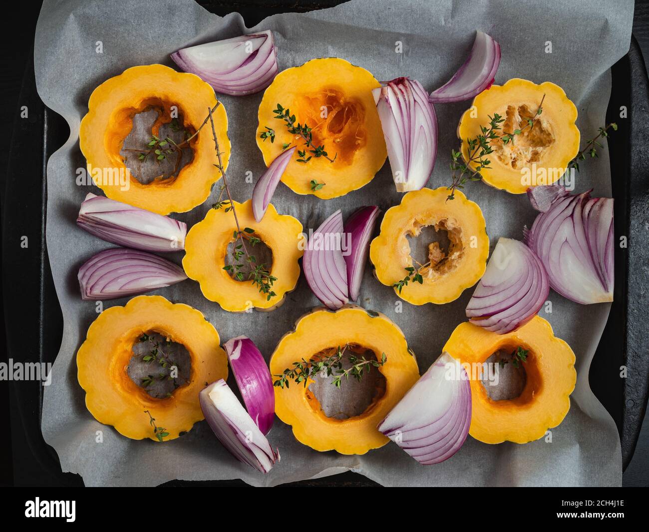 Slices of delicata squash and red onions on a baking sheet. Stock Photo