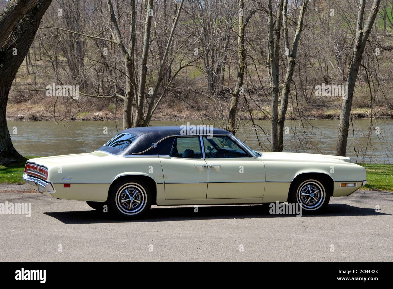 Yellow 1970 Thunderbird Landau sedan rear three-quarter view in park along river Stock Photo