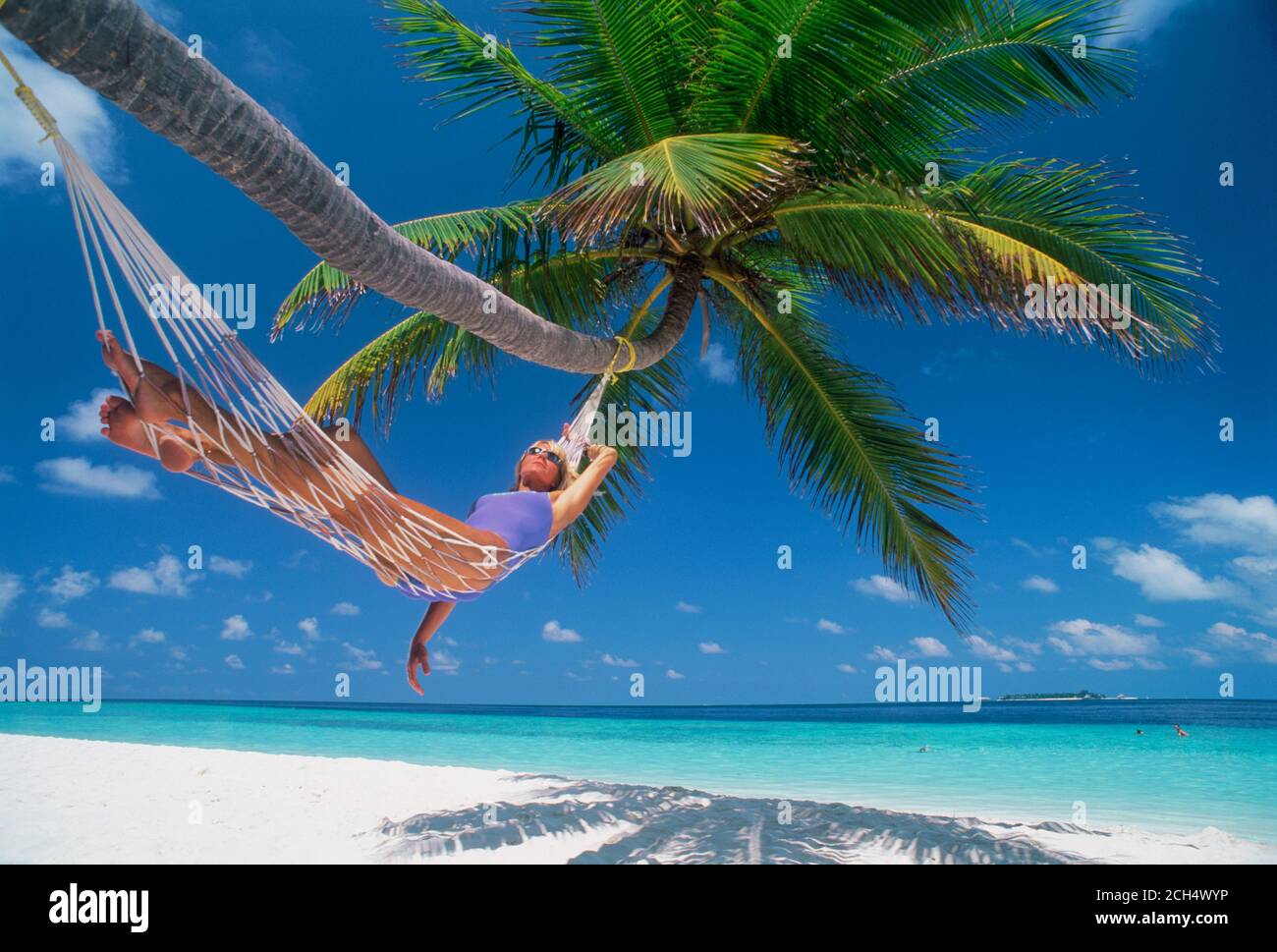 Woman in hammock under palm tree in Maldive Islands Stock Photo
