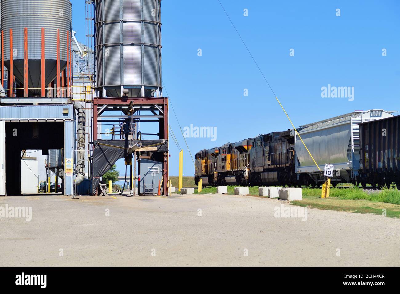 Ashton, Illinois, USA. Three locomotives ead a Union Pacific freight train past a grain elevator complex. Stock Photo