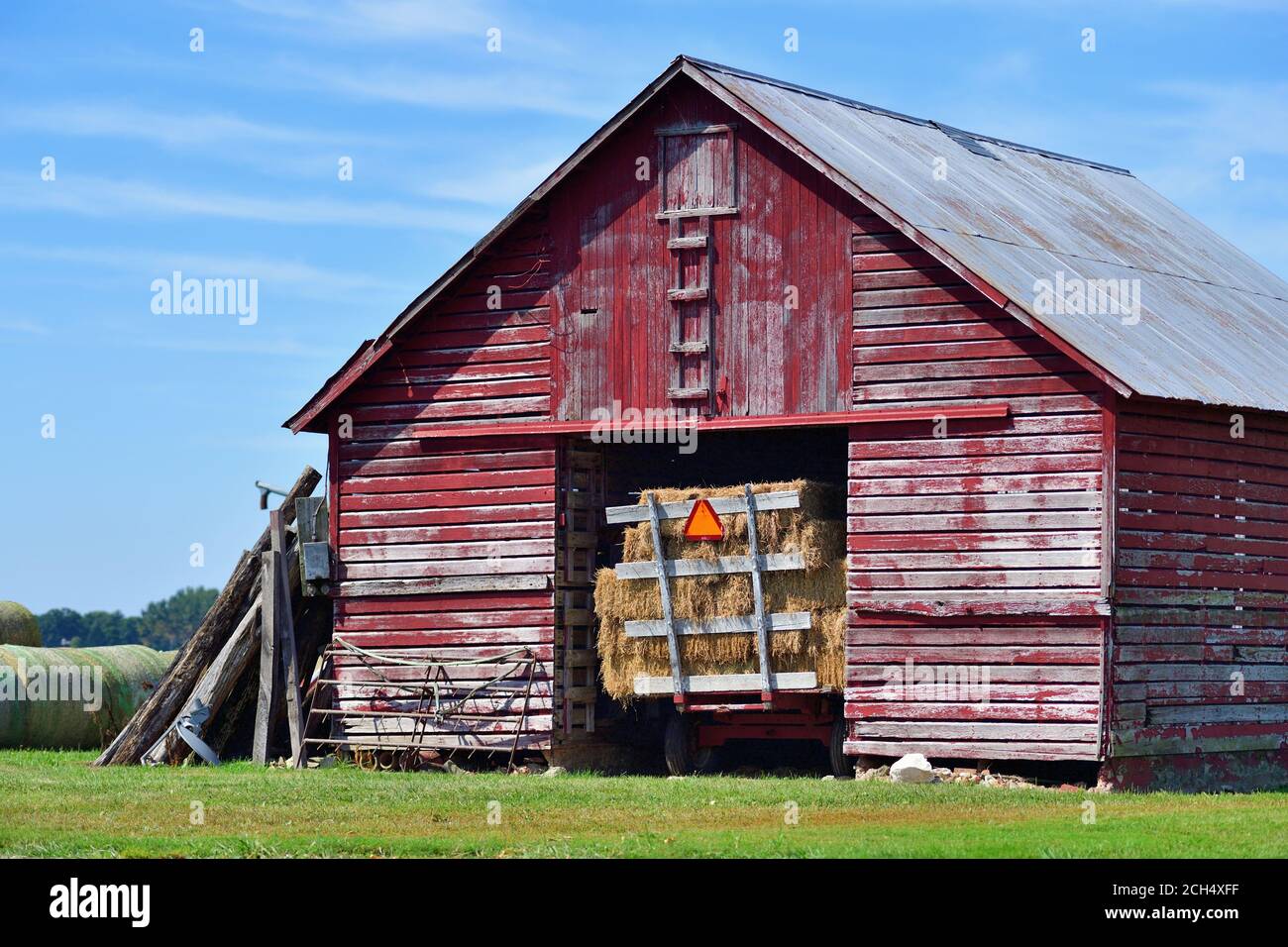 Lacon, Illinois, USA. An old red, wooden barn containing a hay wagon. The rural scene is from north central Illinois in the Illinois River Valley. Stock Photo