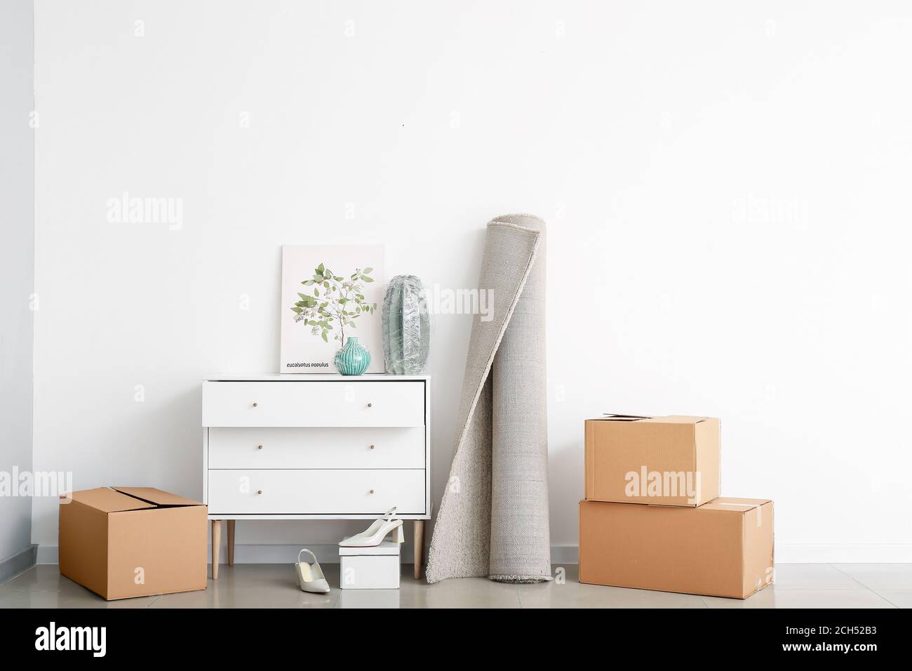 Cardboard boxes with belongings and chest of drawers in new flat on