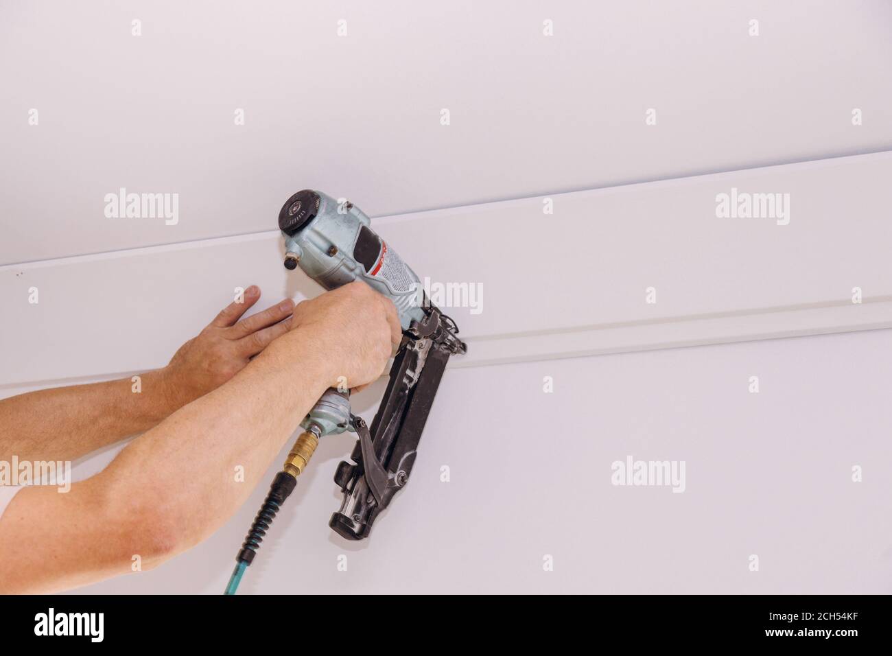 Installation of crown moldings trim on the ceiling of the using gauge