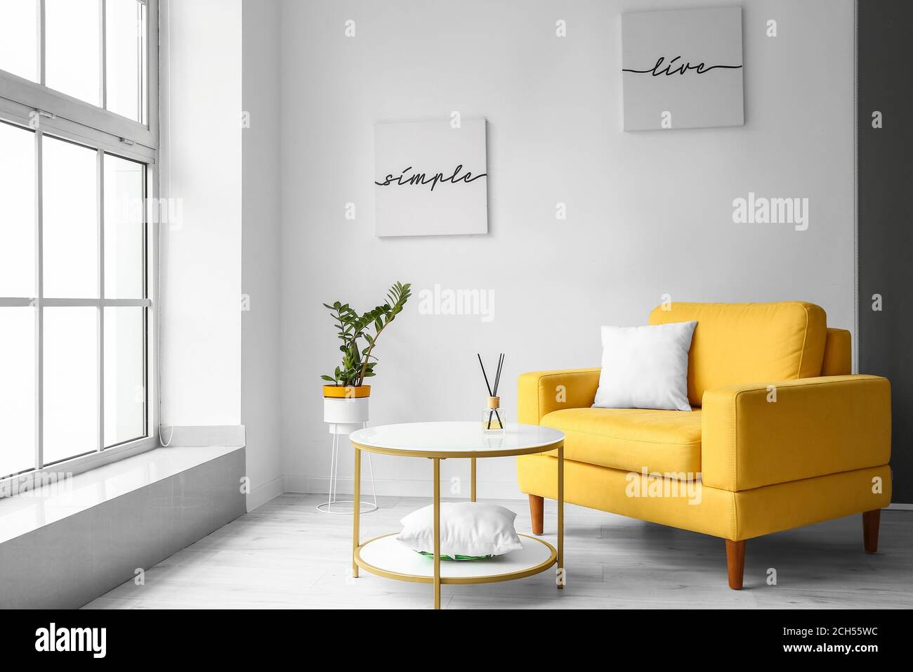 Stylish interior of living room with table and armchair Stock Photo - Alamy