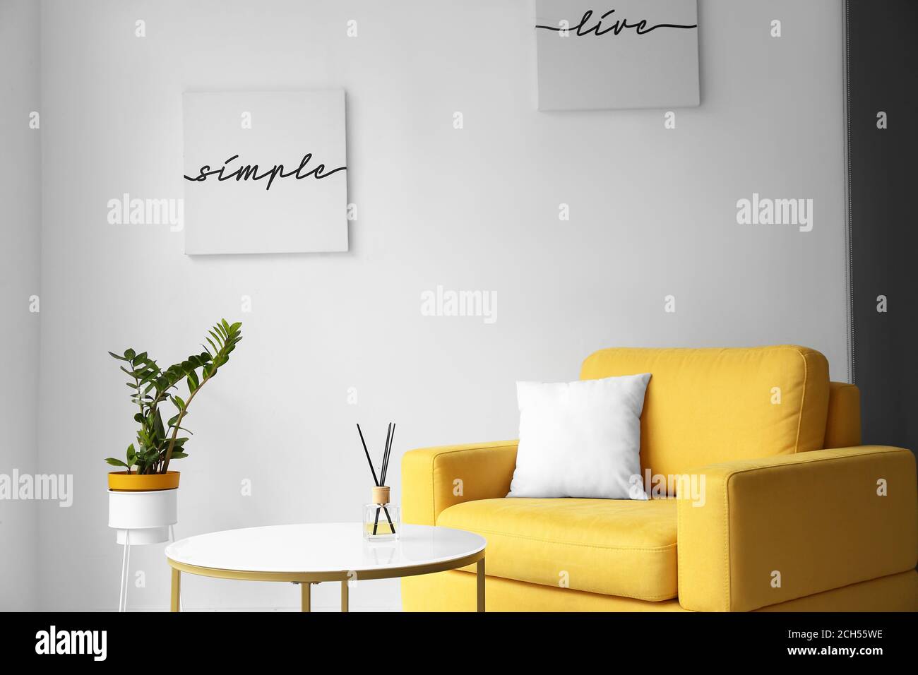 Stylish interior of living room with table and armchair Stock Photo - Alamy