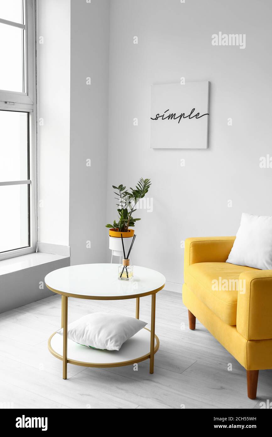 Stylish interior of living room with table and armchair Stock Photo - Alamy
