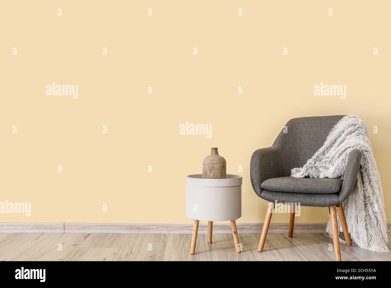 Stylish interior of living room with table and armchair Stock Photo - Alamy