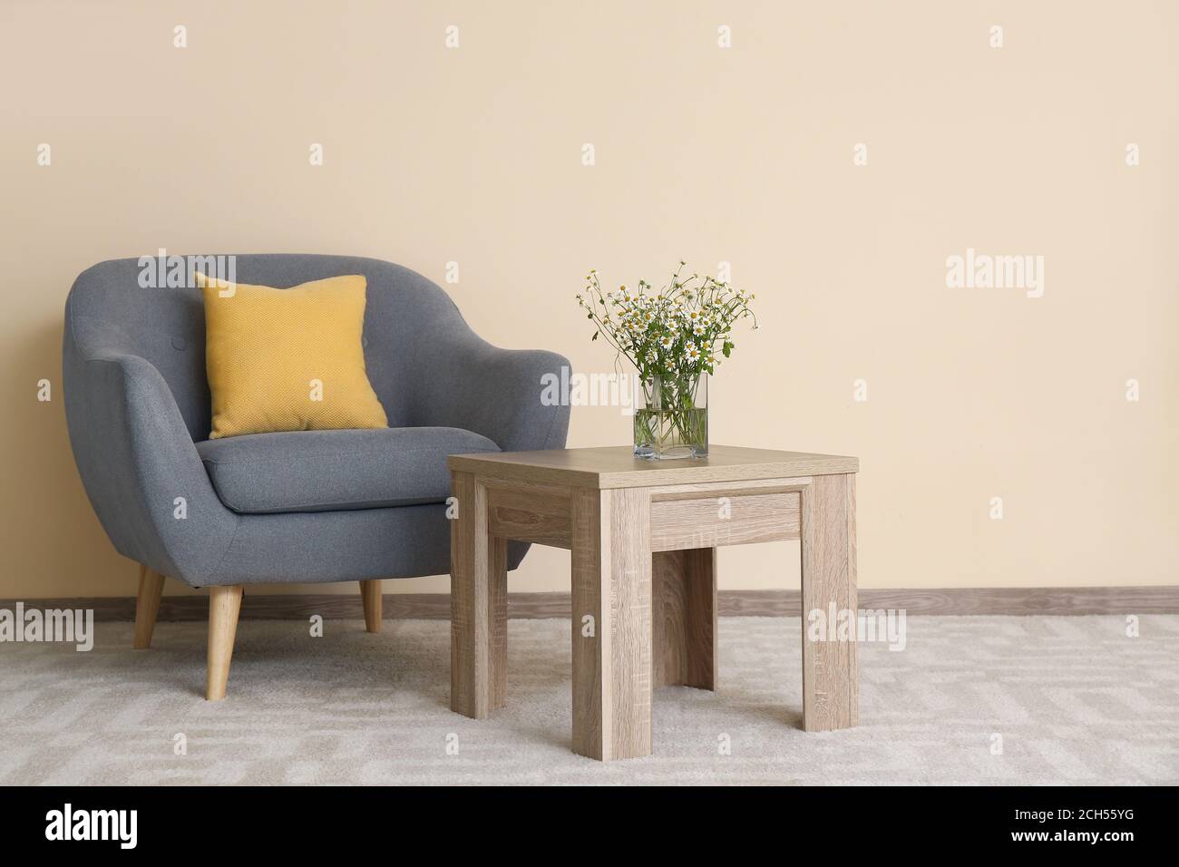 Stylish interior of living room with table and armchair Stock Photo - Alamy