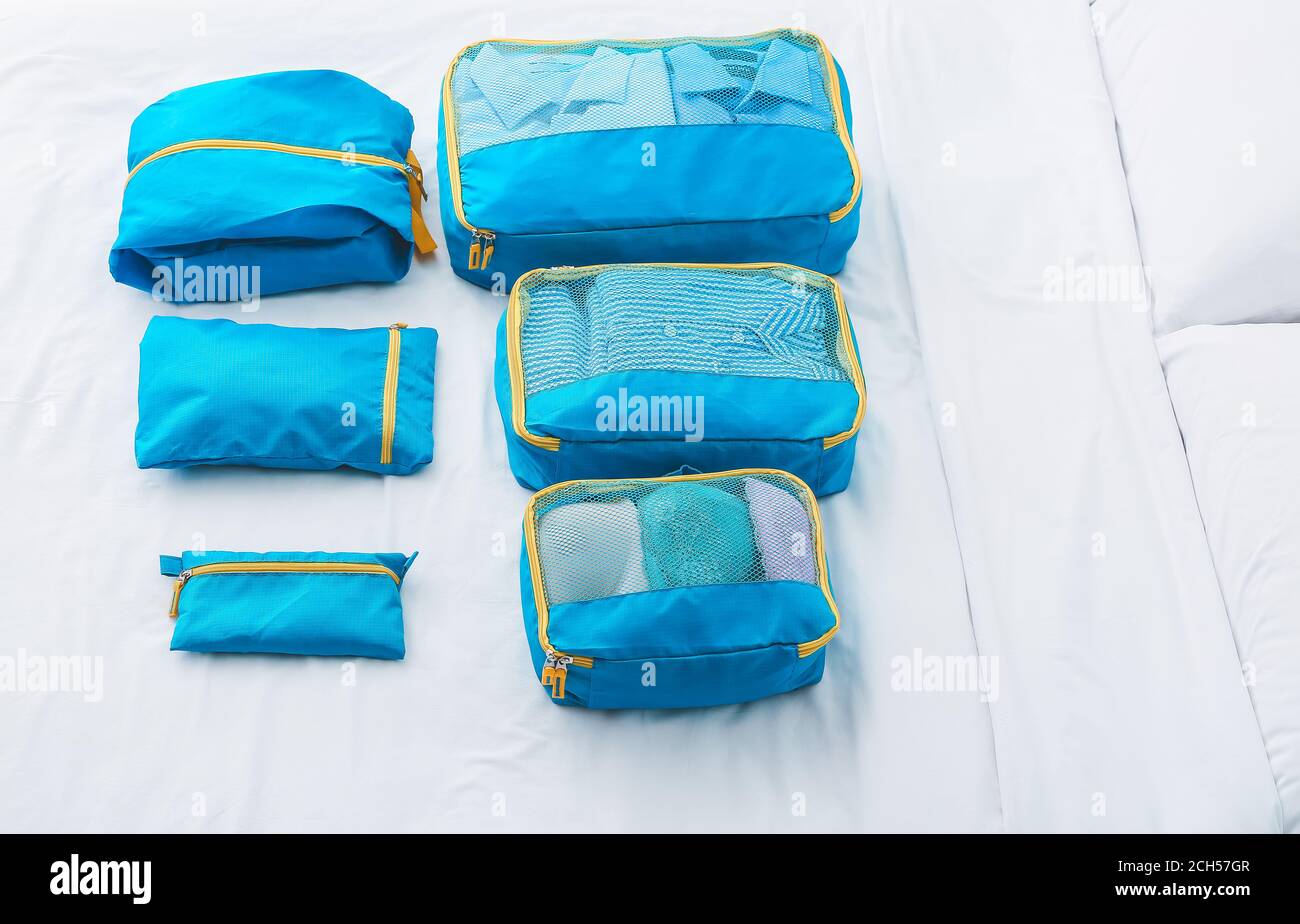 Set of travel organizers with belongings on bed at home Stock Photo