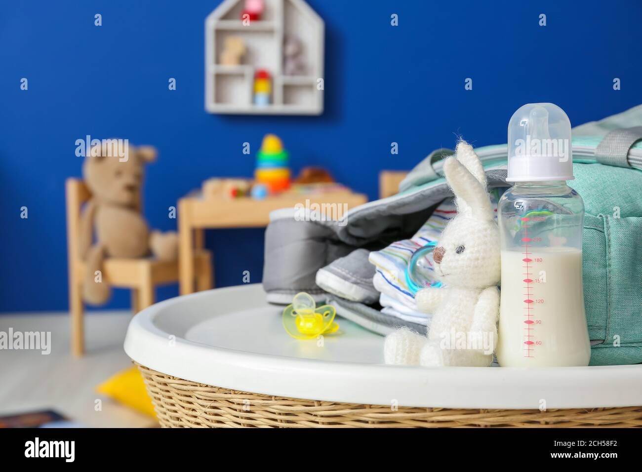 Bottle of milk for baby with accessories on table in room Stock Photo