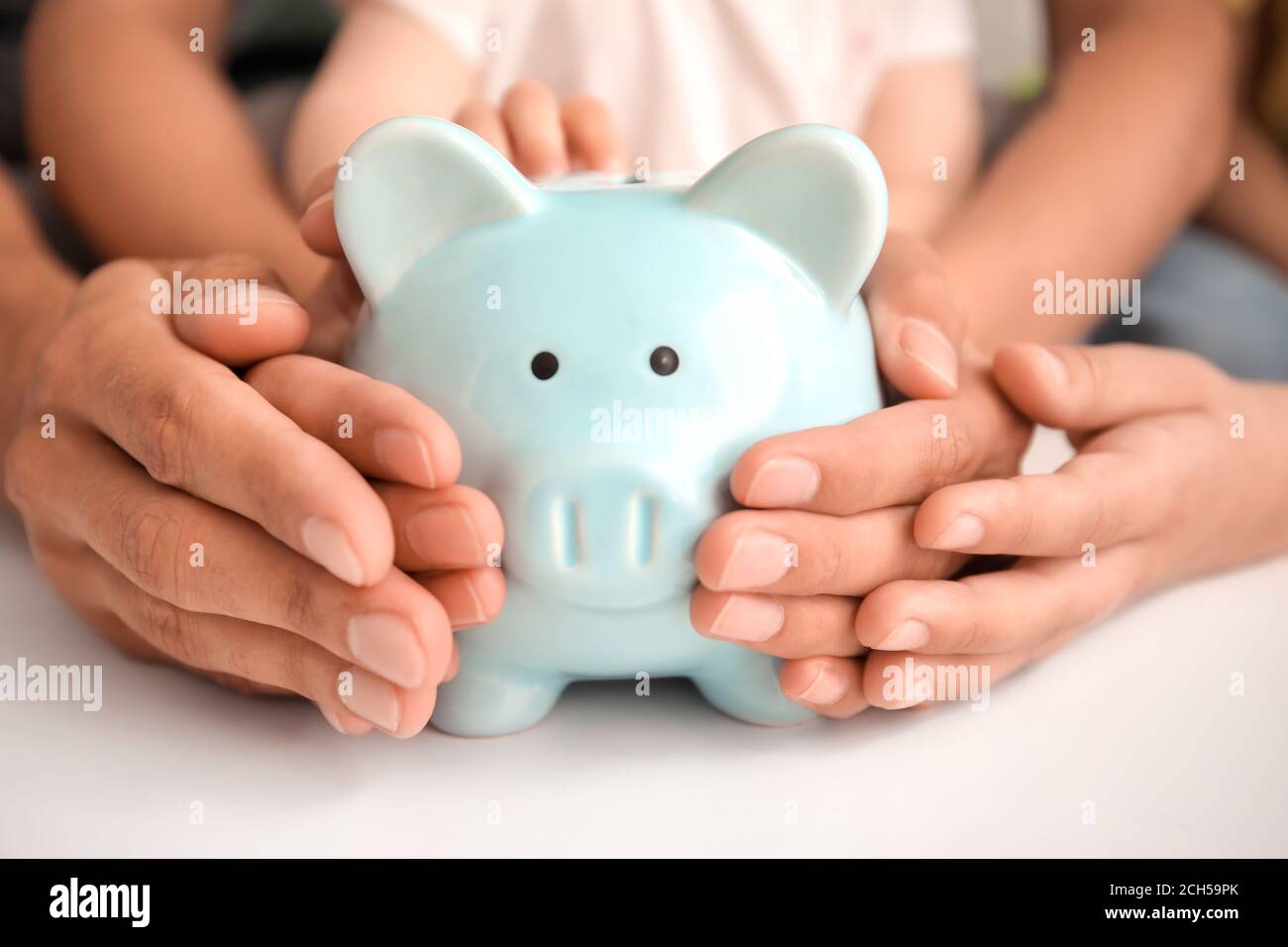 Family with piggy bank at table Stock Photo - Alamy