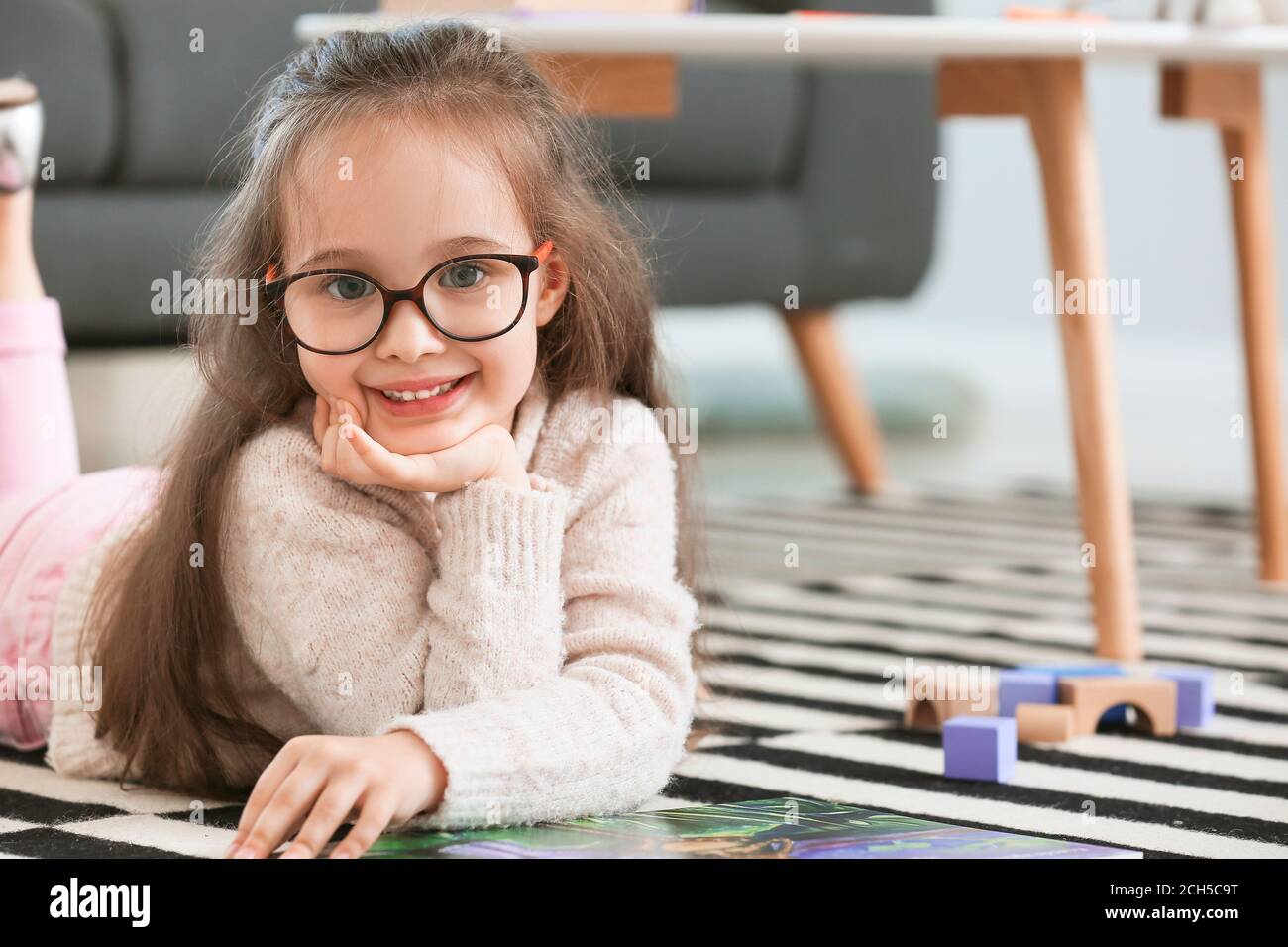 Cute little girl reading book at home Stock Photo - Alamy