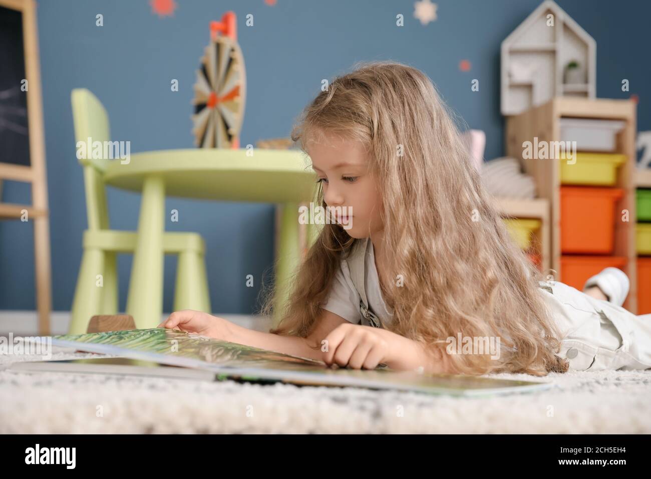 Cute little girl reading book at home Stock Photo - Alamy