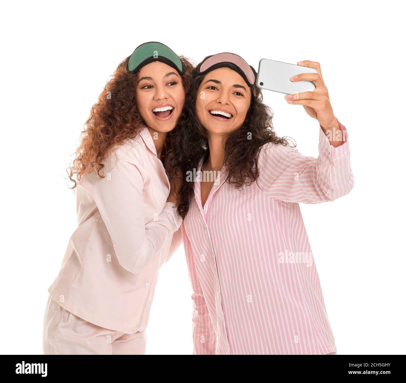 Beautiful young women in pajamas taking selfie on white background ...