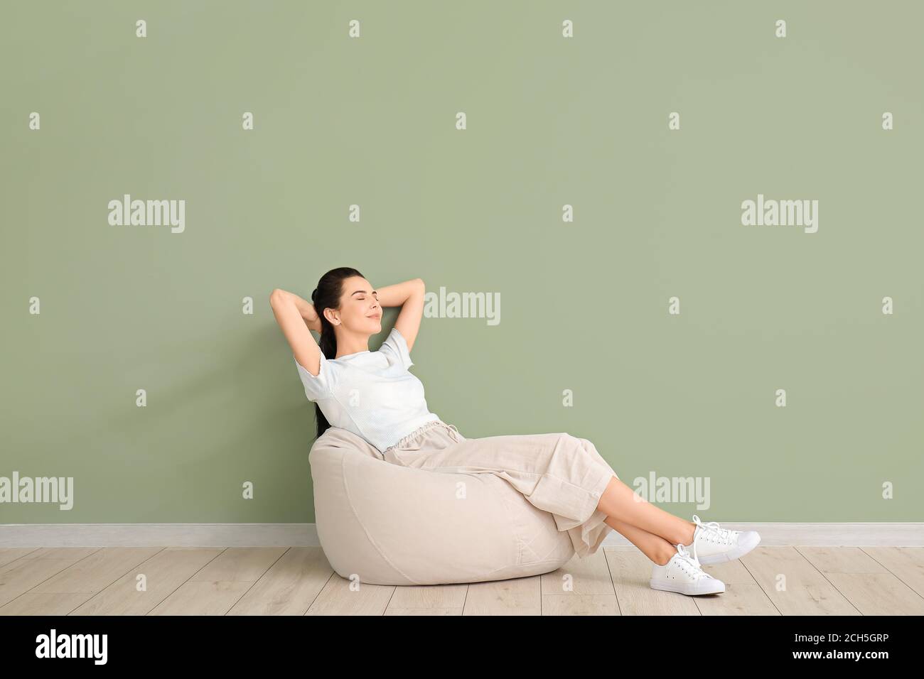 Young woman relaxing on beanbag near color wall Stock Photo - Alamy