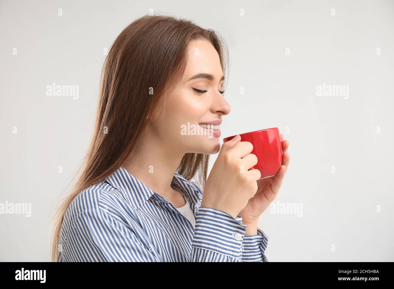 Beautiful young woman with cup of tea on light background Stock Photo ...