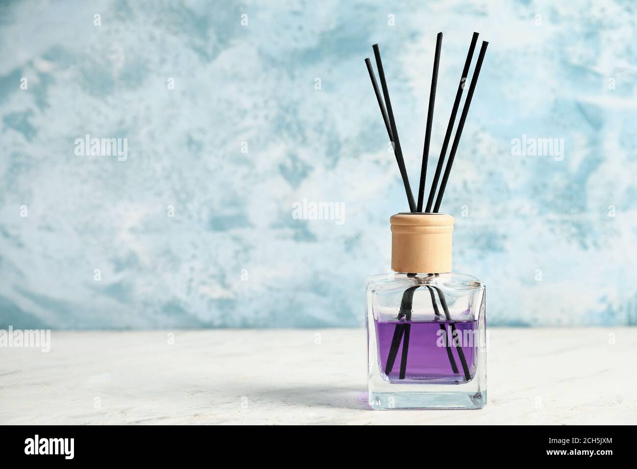 Reed diffuser on table against color background Stock Photo