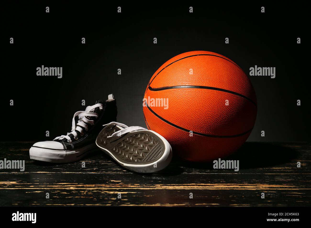Ball for playing basketball and shoes on dark background Stock Photo