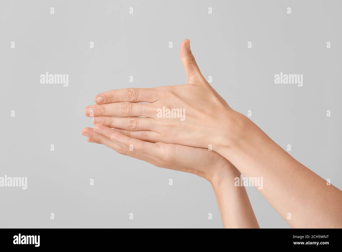 Young deaf mute woman showing sign STOP on grey background Stock Photo