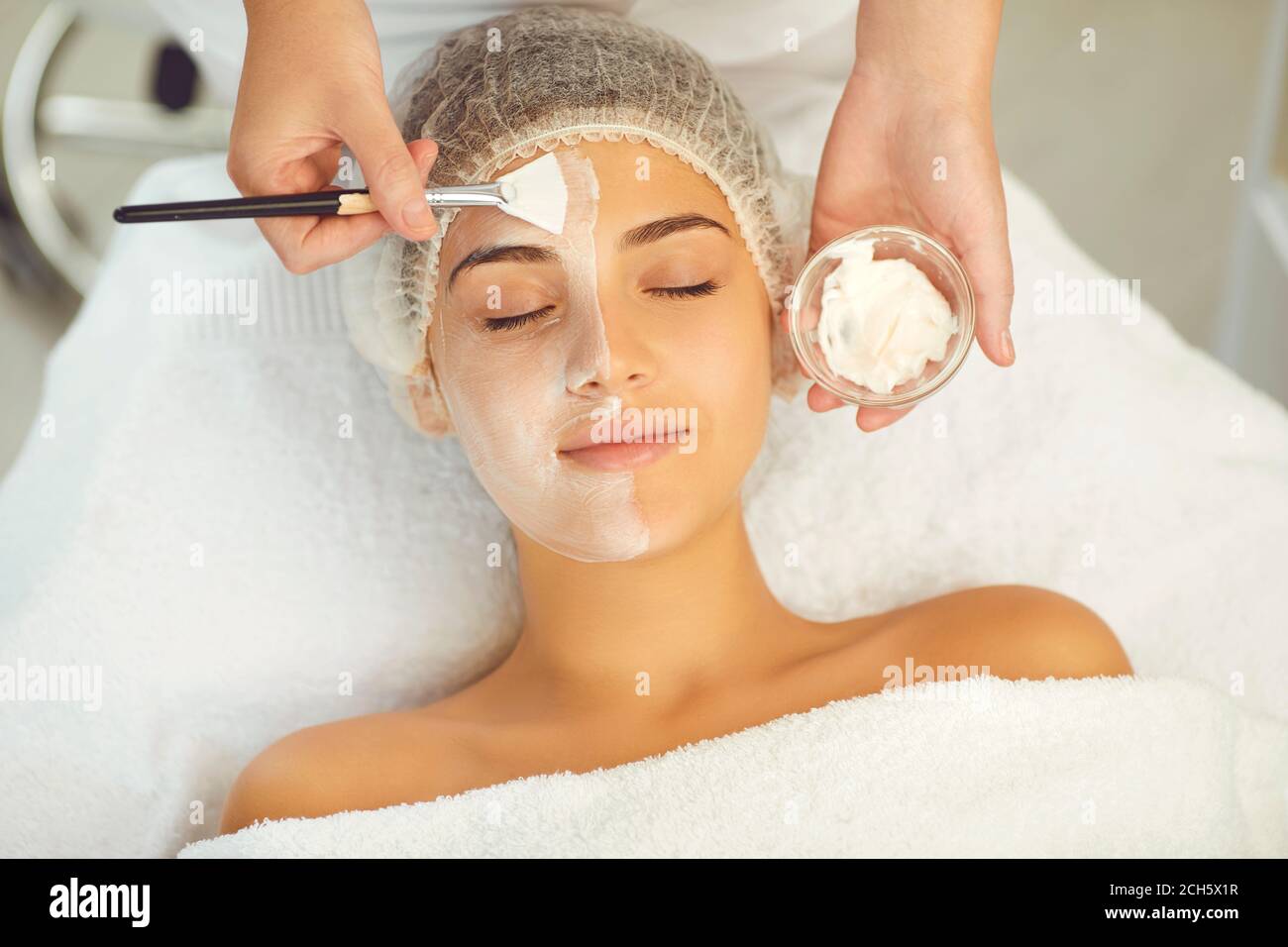 Dermatologist putting moisturizing mask to womans face during skincare procedure Stock Photo