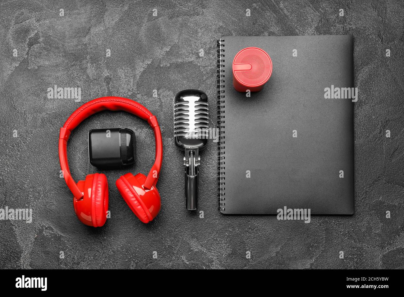 Headphones with microphone, notebook and speakers on dark background
