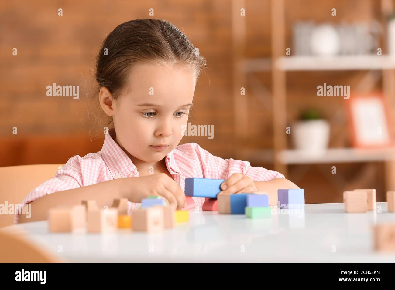 Little girl with autistic disorder playing with blocks at home Stock