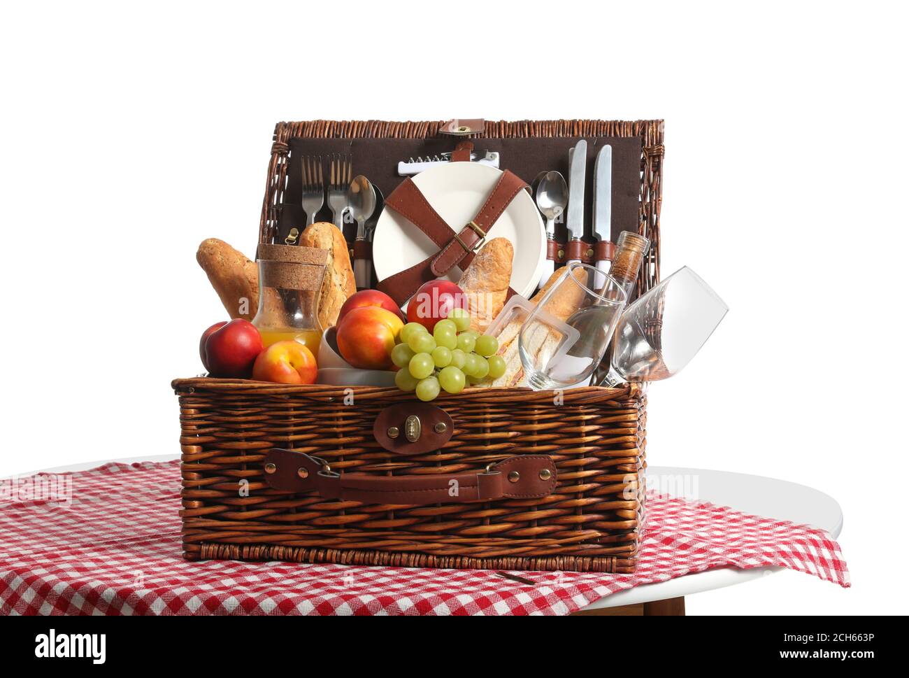 Wicker basket with tasty food and drink for picnic on white background ...