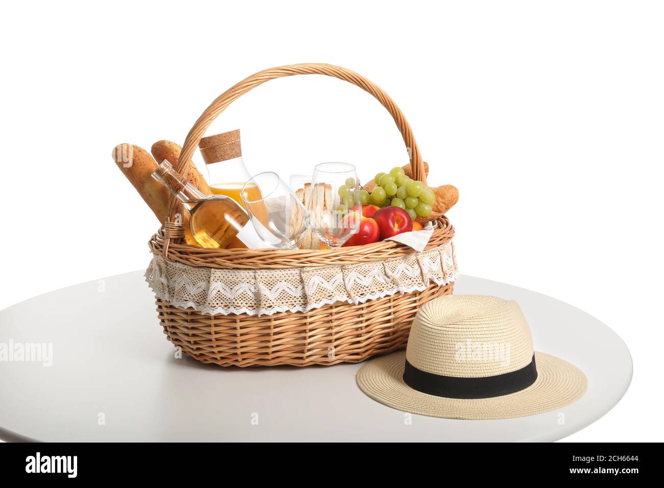 Wicker basket with tasty food and drink for picnic on white background ...