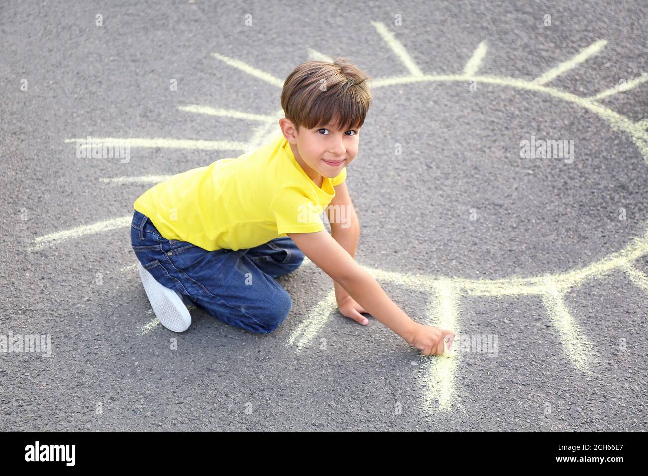 Little boy drawing sun with chalk on asphalt Stock Photo - Alamy