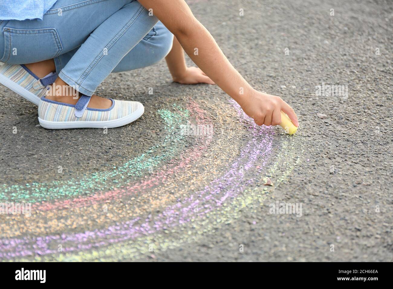Little girl drawing rainbow with chalk on asphalt Stock Photo - Alamy