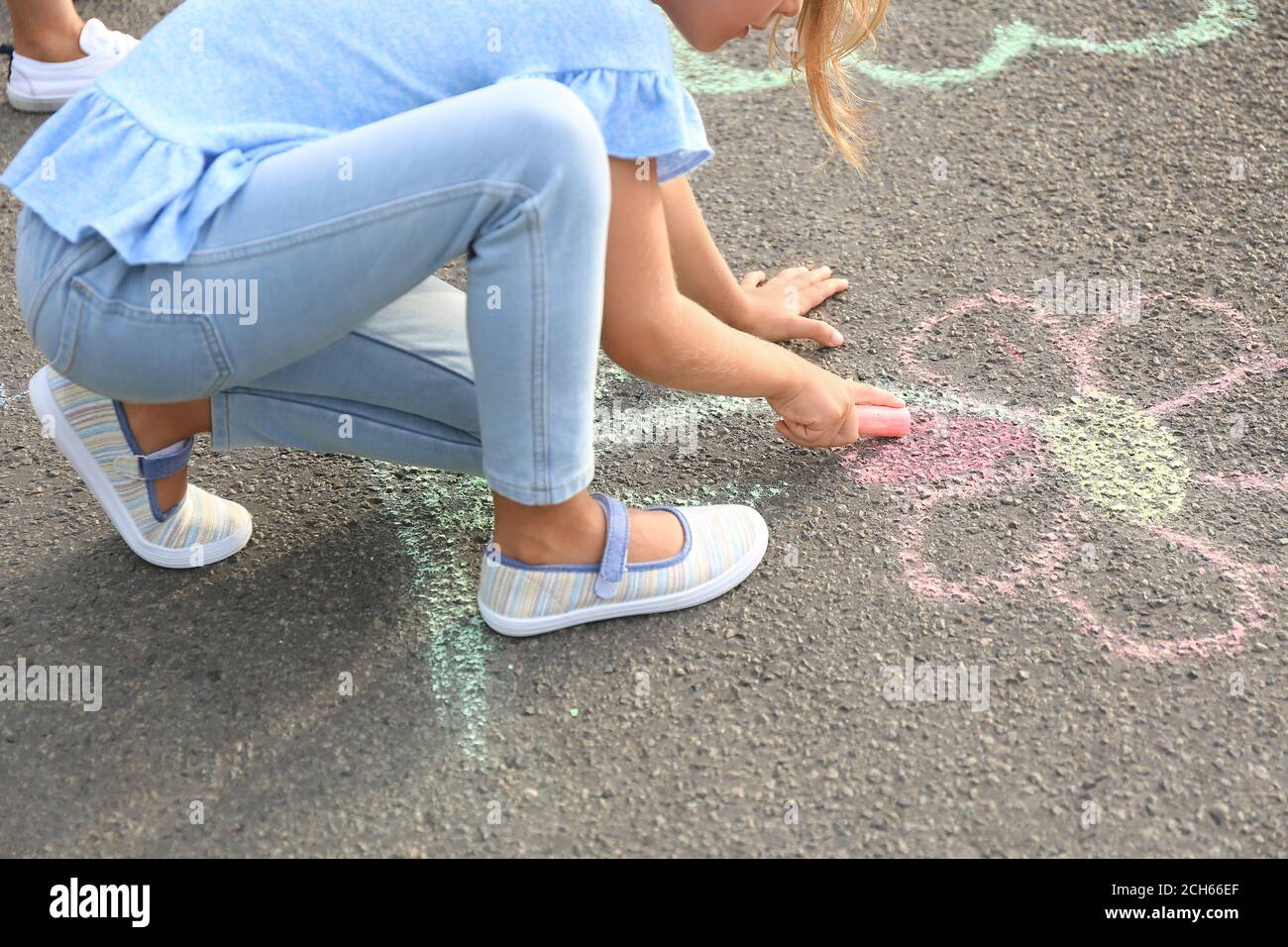 Little girl drawing flower with chalk on asphalt Stock Photo - Alamy