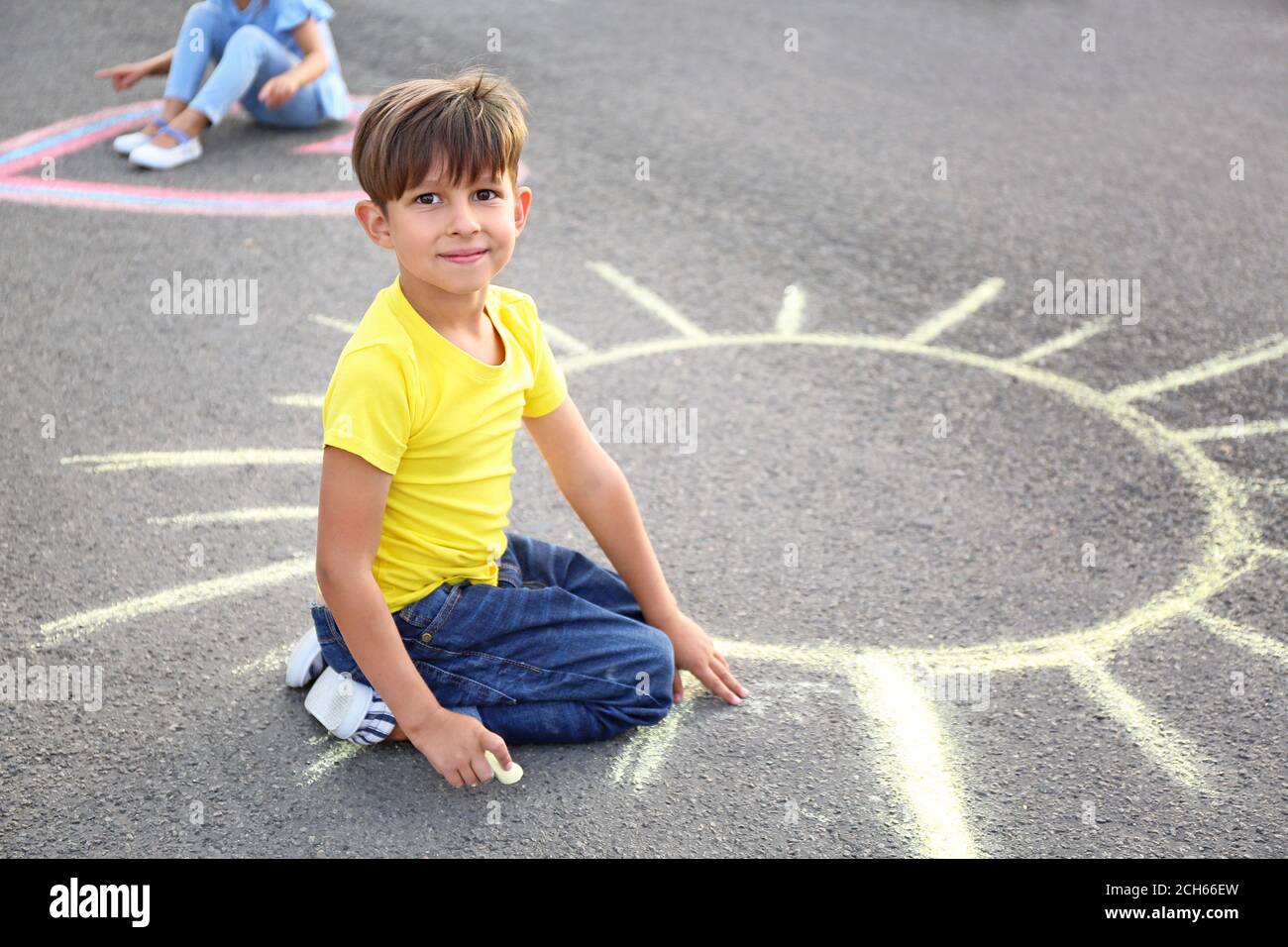Little boy drawing sun with chalk on asphalt Stock Photo - Alamy