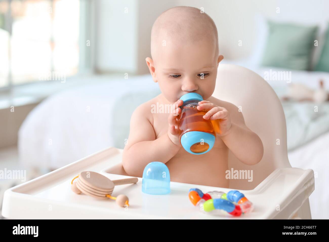 Cute little baby drinking juice from bottle at home Stock Photo