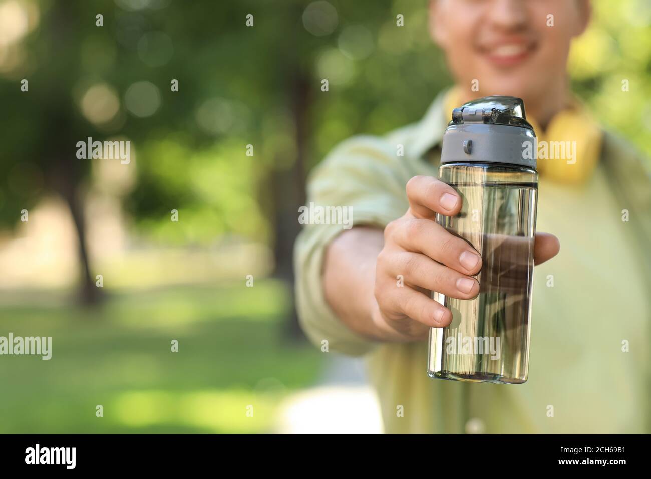 Young man with bottle of water in park, closeup Stock Photo - Alamy