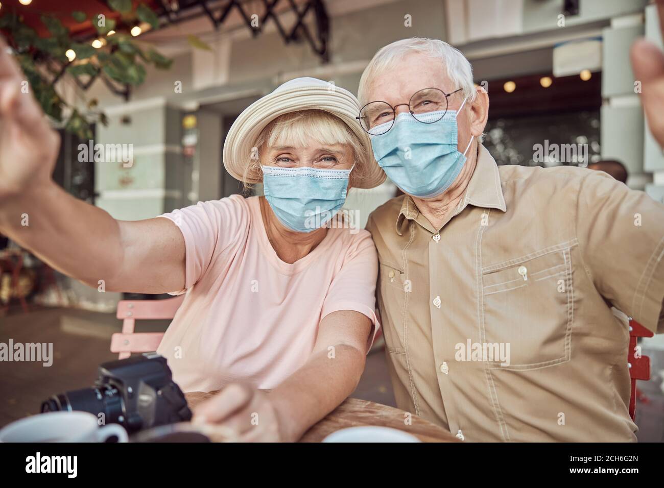Elderly couple in protective masks sitting in a cafe Stock Photo