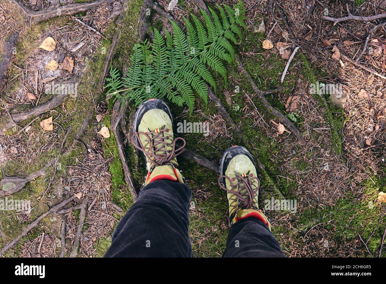 Hiking boots in outdoor action. Top View of Boot on the trail. Close-up Legs In Jeans And sport trekking shoes on rocky srones of Mountain river Stock Photo