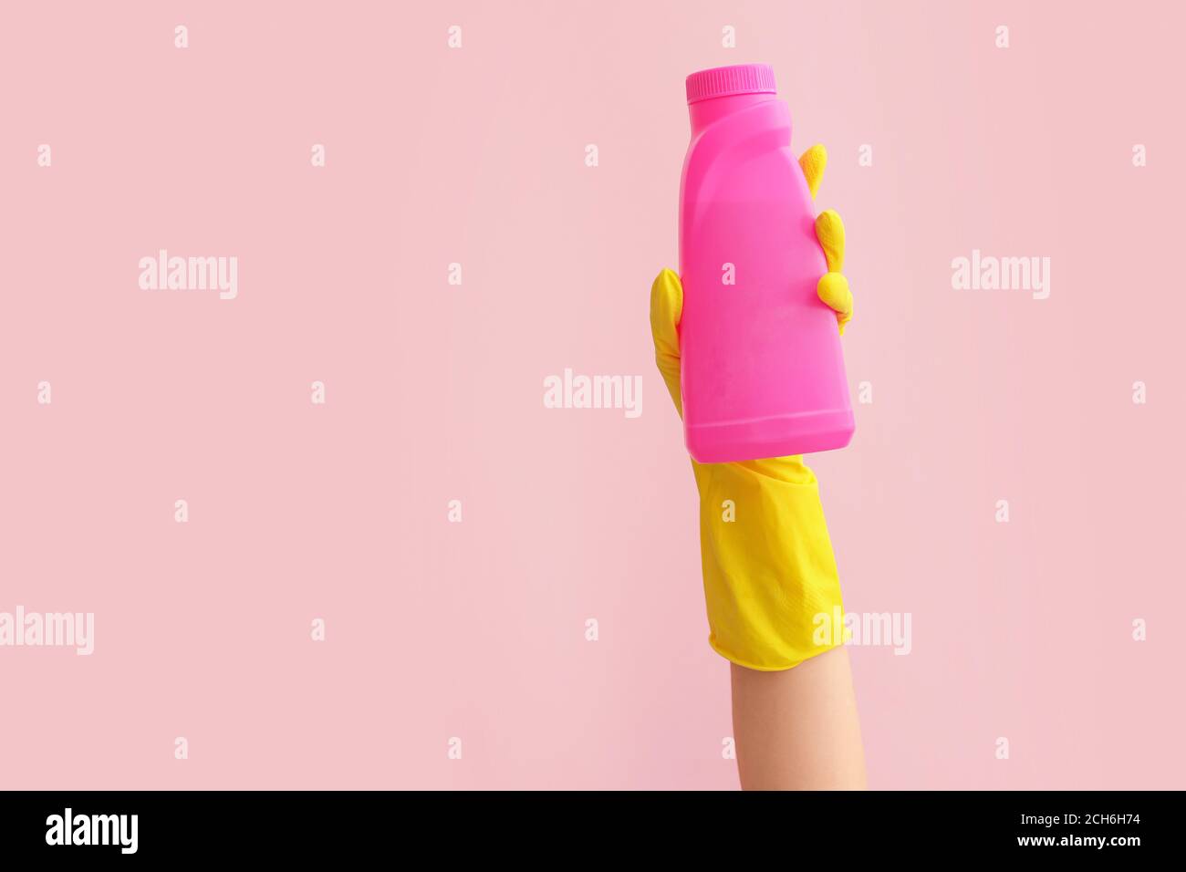 Hand in rubber glove holding detergent on color background Stock Photo ...