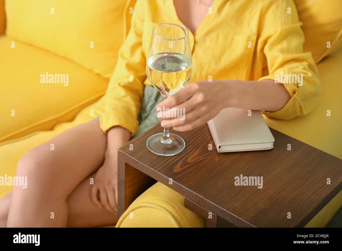 Woman with glass of wine resting on sofa at home Stock Photo