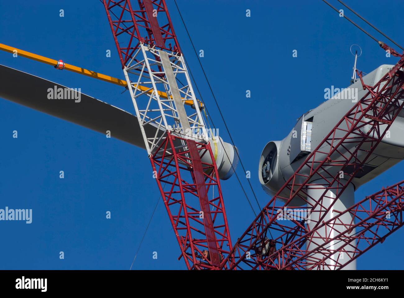 Giant crane lifting wind turbine blade to attach to nacelle during