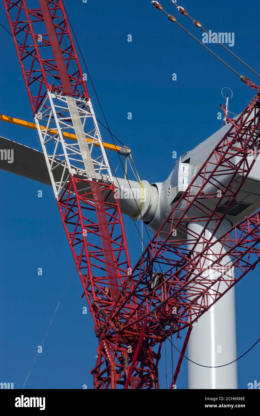 Giant crane lifting wind turbine blade to attach to nacelle during