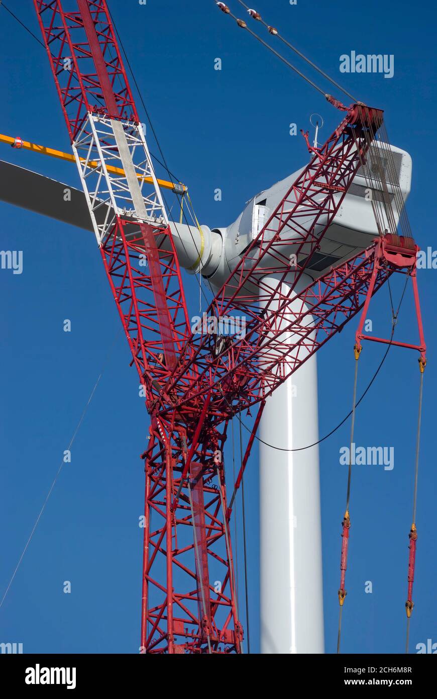 Giant crane lifting wind turbine blade to attach to nacelle during