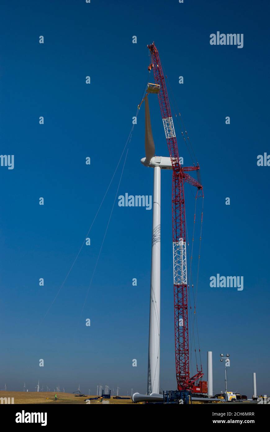 Giant crane lifting wind turbine blade to attach to nacelle during