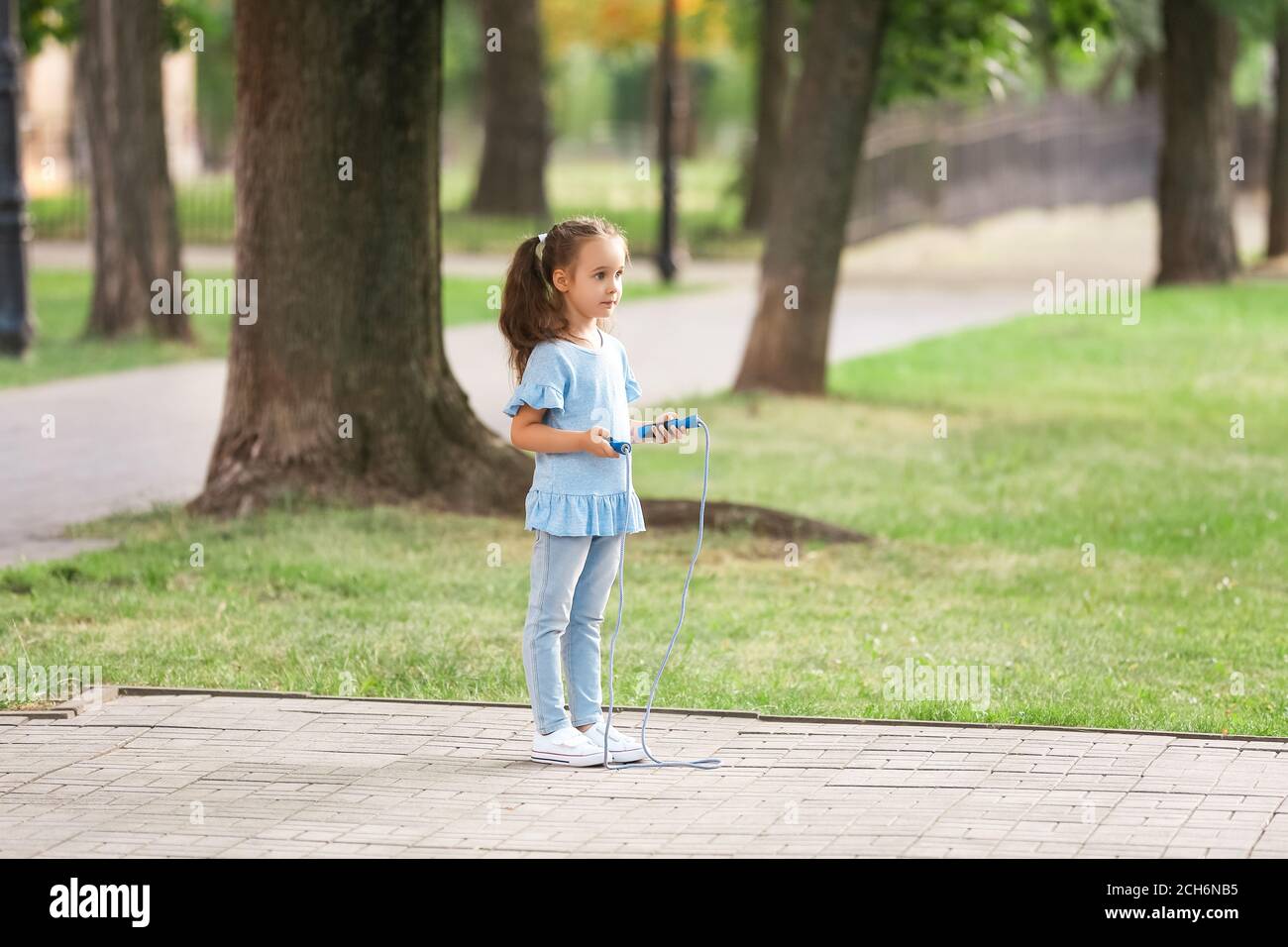 Cute little girl jumping rope outdoors Stock Photo - Alamy