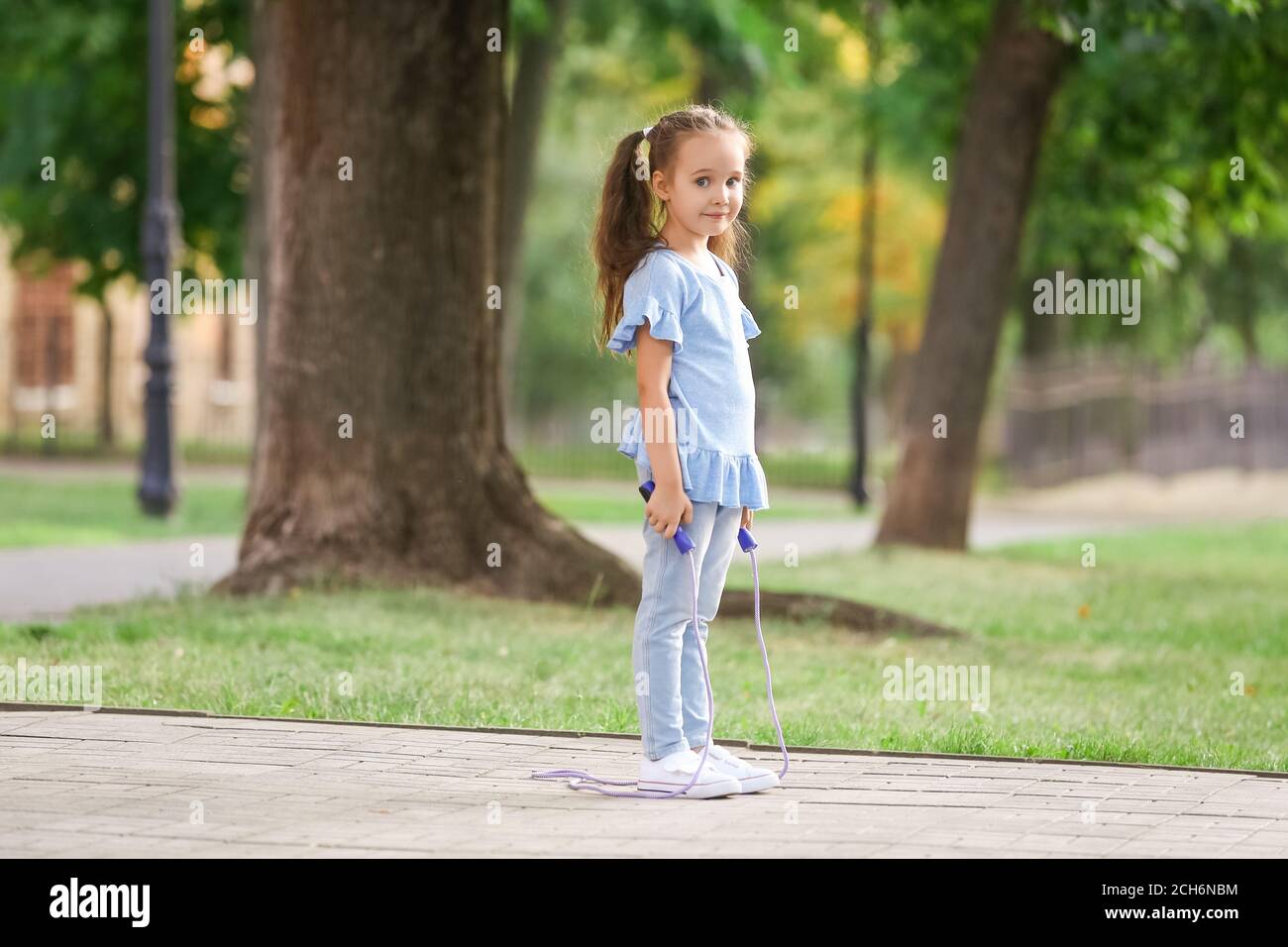 Cute little girl jumping rope outdoors Stock Photo - Alamy