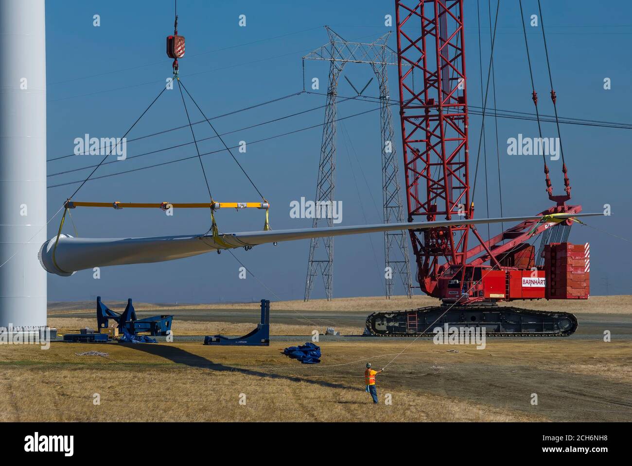 Giant crane lifting wind turbine blade to attach to nacelle during