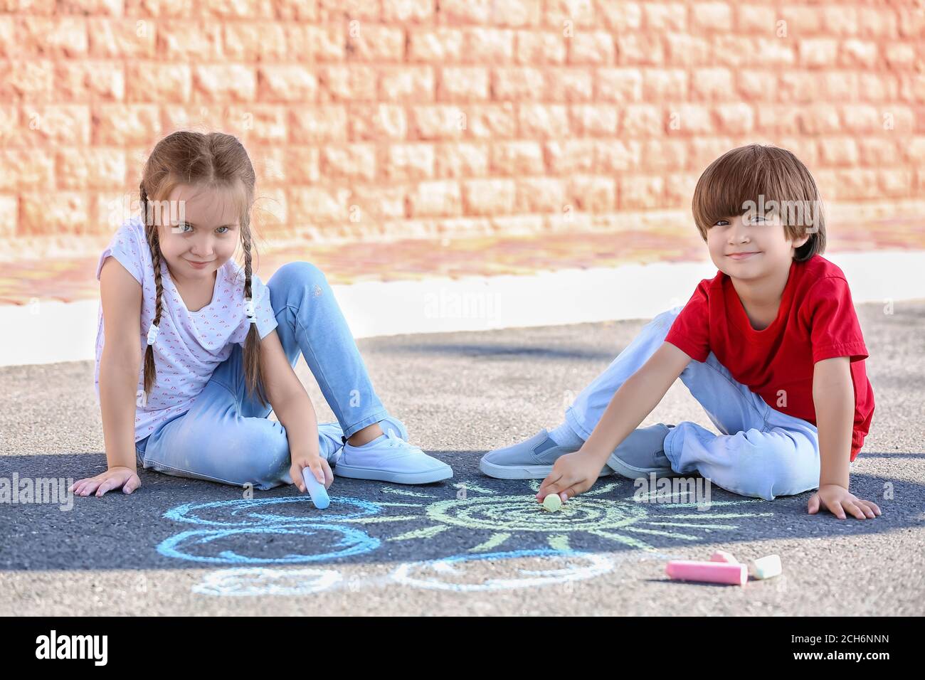 Little children drawing with chalk on asphalt Stock Photo - Alamy